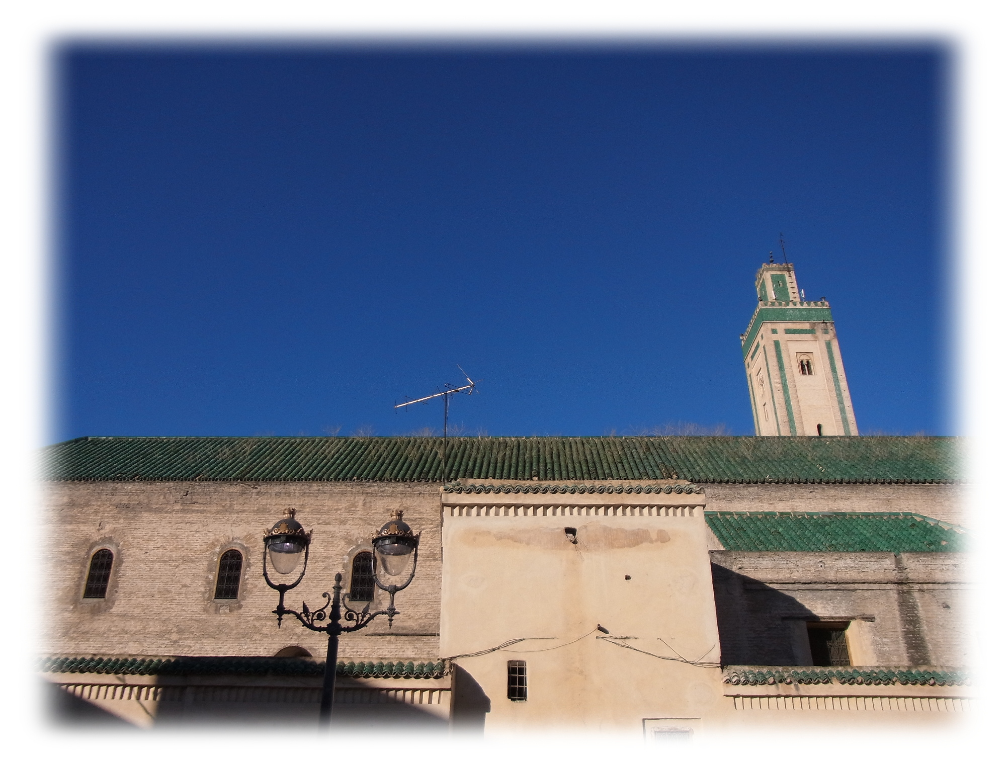 Green roof of Kairaouine Mosque of Fes with the minaret of Bou Inania Madrasa